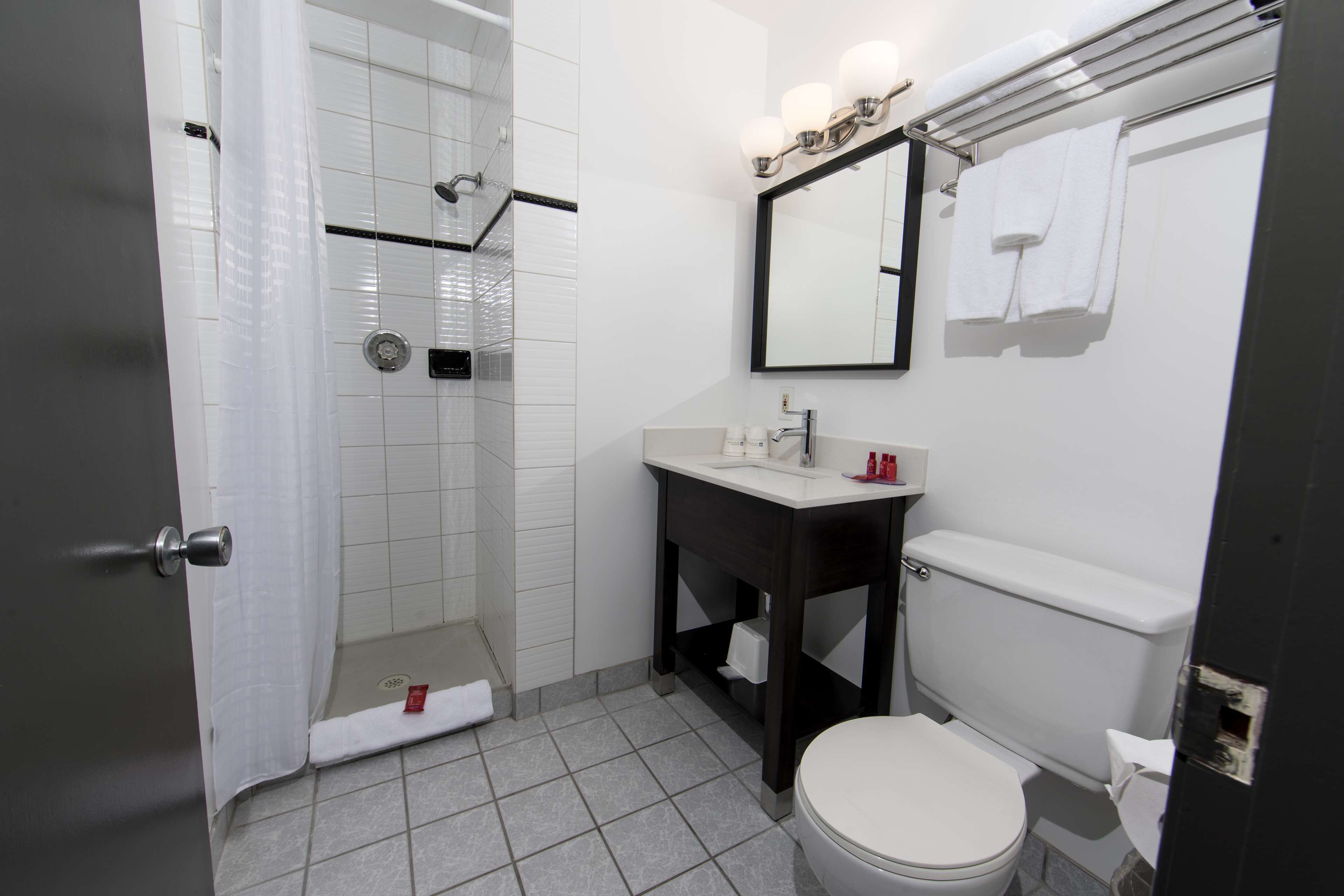 Un baño con ducha, inodoro, lavamanos y un espejo con iluminación.