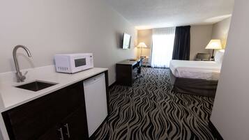 Una habitación de hotel con kitchenette, una cama, un escritorio y un baño.