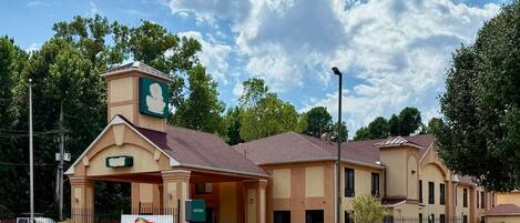 A hotel with a prominent entrance, a signboard, and a clear sky.