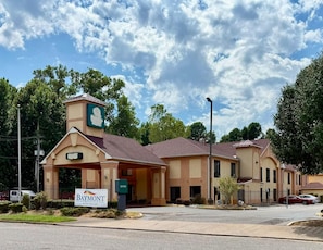 A hotel with a prominent entrance, a signboard, and a clear sky.