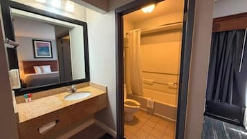 A bathroom with a sink, mirror, and a shower area visible through an open door.