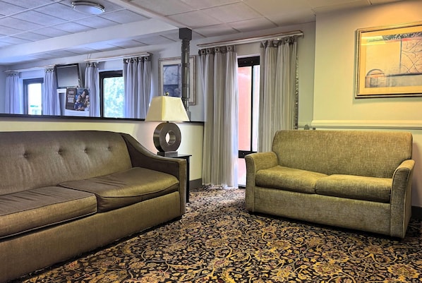 A room with a sofa, a chair, a lamp, a patterned carpet, and a painting on the wall. - Baymont by Wyndham Memphis I-40 (Memphis)