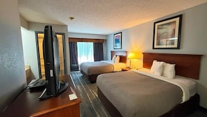 Une chambre d’hôtel avec deux lits, un bureau avec un ordinateur et une télévision.