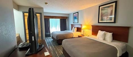 A hotel room with two beds, a desk with a computer, and a television.