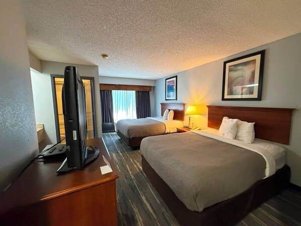 A hotel room with two beds, a desk with a computer, and a television.