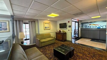 Un hall de hotel con un sofá, una mesa de centro, un televisor y una recepción.