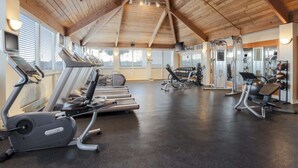 Une salle de sport équipée de tapis de course, de vélos elliptiques et de matériel de musculation.