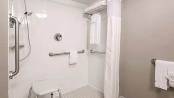 A shower area with a grab bar, a white step stool, and a towel rack.