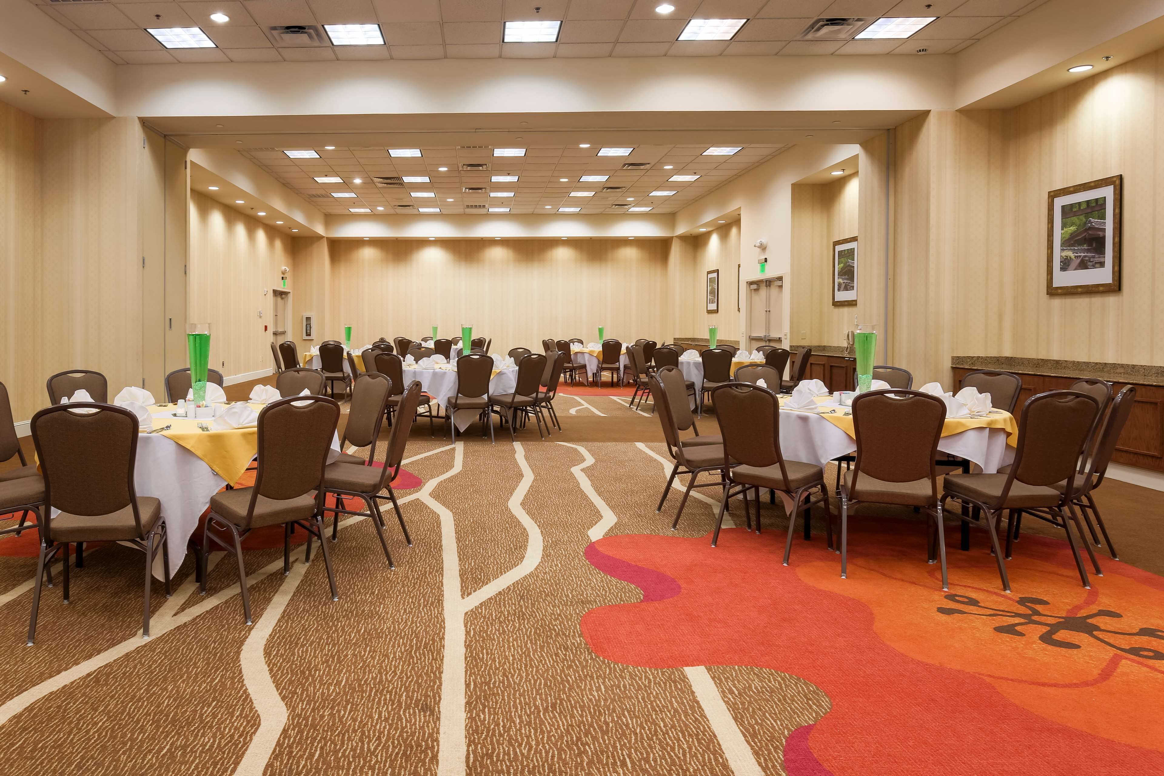 Une grande salle de conférence, dotée de nombreuses tables et chaises disposées en rangées.