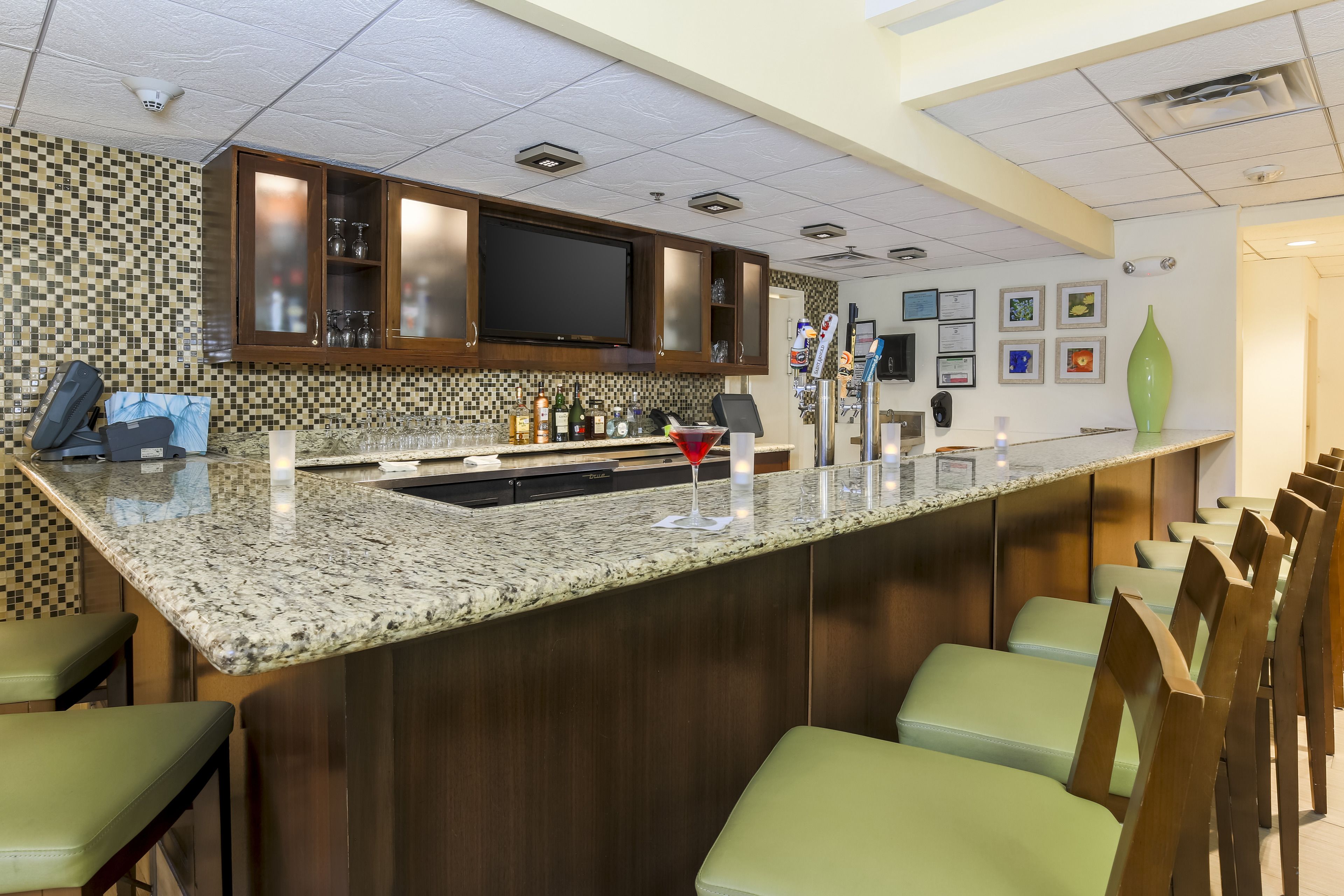 A bar area with a granite countertop, bar stools, and a television above the bar.
