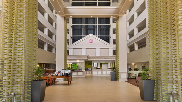 Un hall d’entrée spacieux avec un comptoir d’accueil central, de nombreux étages et de grandes fenêtres.