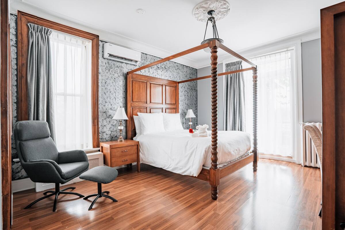 Une chambre à coucher avec un lit à baldaquin, une table de chevet en bois, une chaise et un bureau avec une lampe.