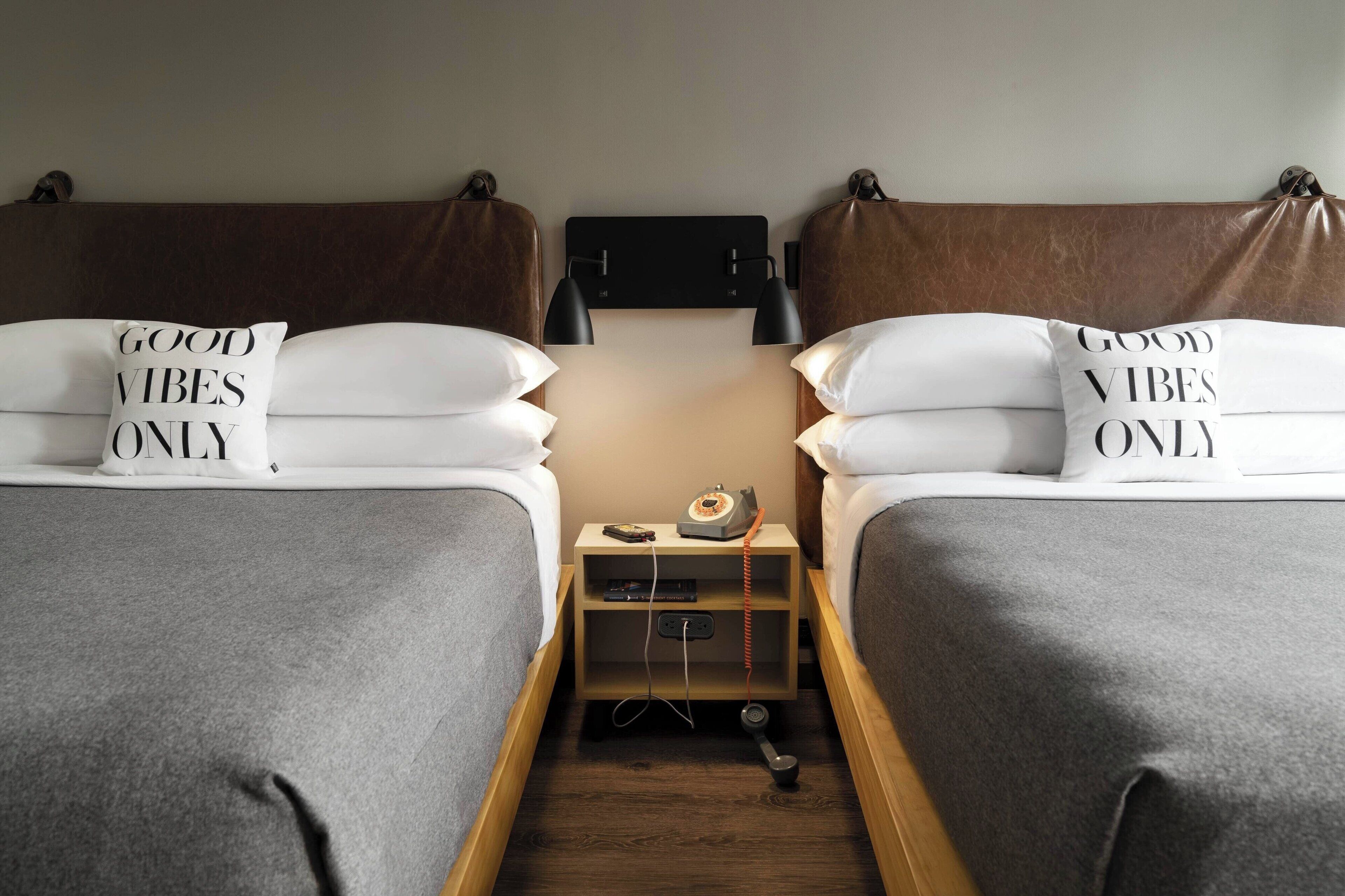 A double bed with a headboard, a bedside table with a lamp, and a nightstand with a telephone.