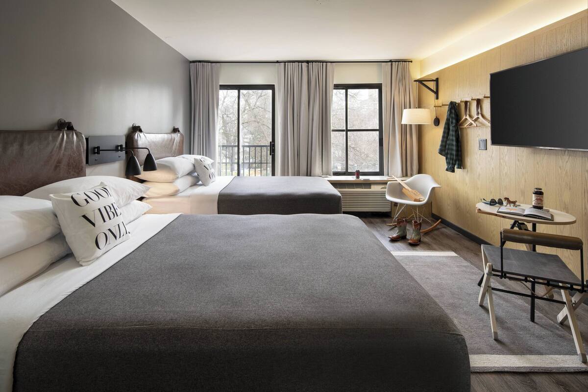 A hotel room with two beds, a TV, a desk, and a chair.