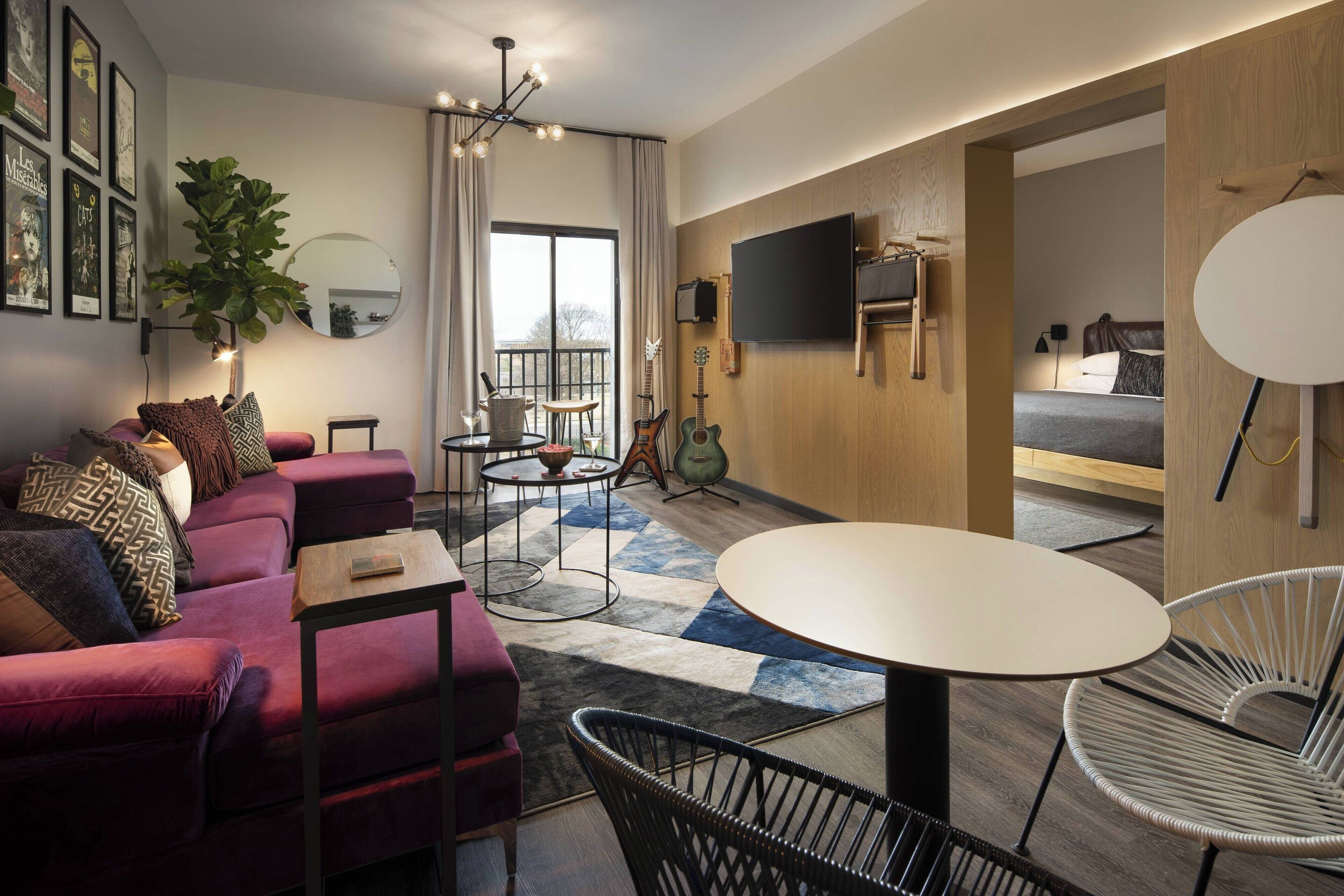 A modern living room with a sofa, a round table, and a TV mounted on the wall.