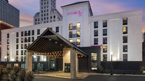 A modern hotel with a prominent neon sign, a covered entrance, and a view of surrounding buildings. - MOXY Memphis Downtown (Memphis)