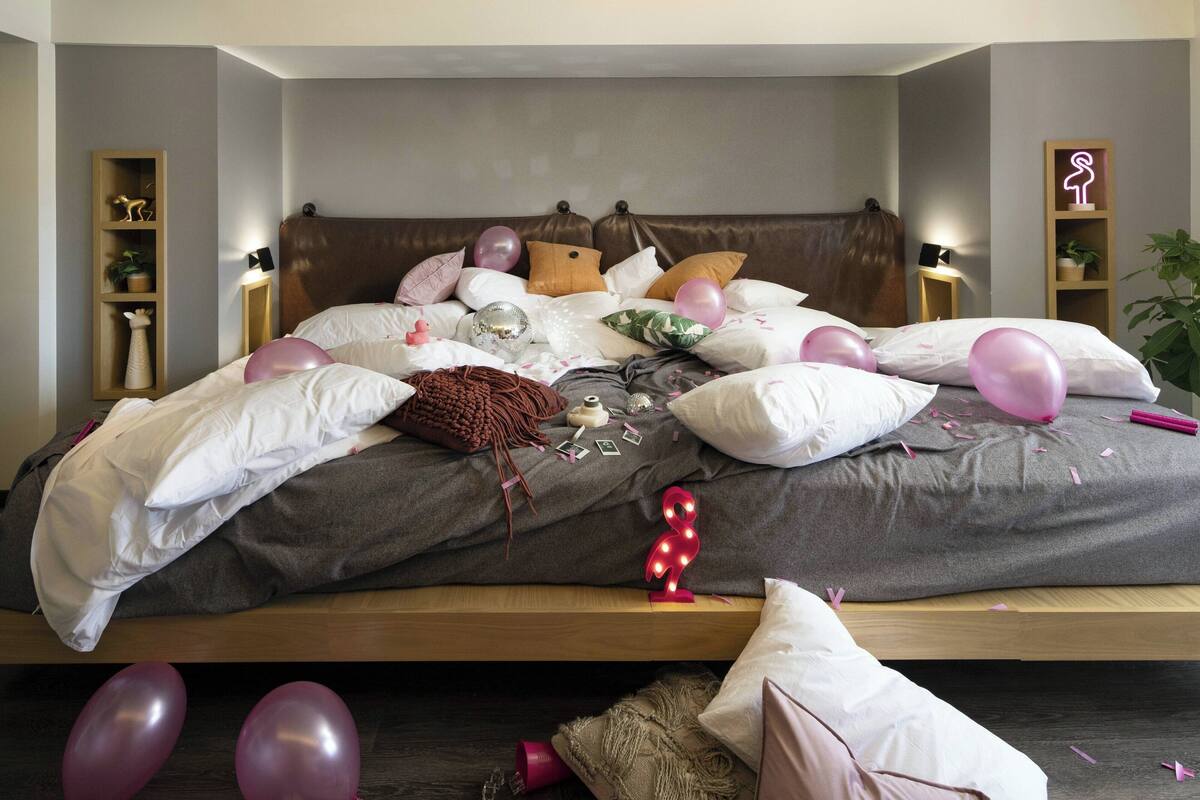 A bedroom with a bed, pillows, and a bedside table.