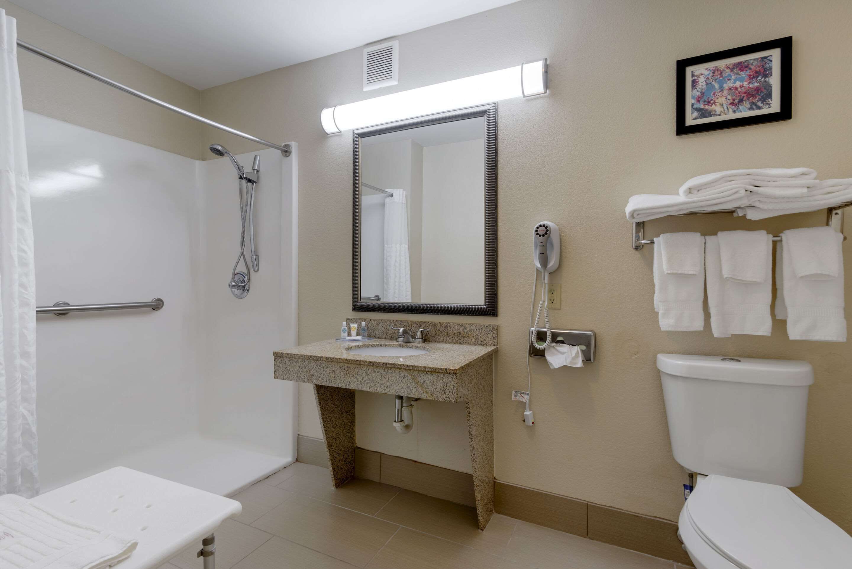 A bathroom with a shower, sink, toilet, and a towel rack.