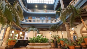 A multi-level atrium with a central fountain, potted plants, and a reception desk.