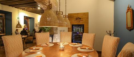 A dining area with a round table, woven placemats, and hanging pendant lights.