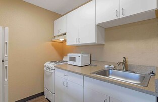 Una cocina compacta con armarios blancos, un microondas, una estufa y un lavabo.