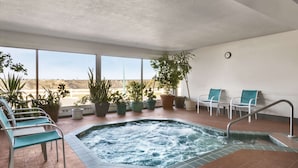 A spa area with a hot tub, seating, and potted plants.