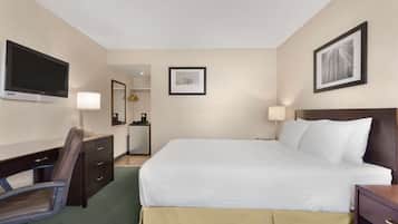 Ein Hotelzimmer mit Bett, Schreibtisch, Stuhl, Fernseher und einem gerahmten Bild an der Wand.
