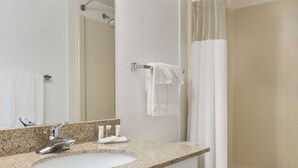 A bathroom with a granite countertop sink, a mirror, a towel rack, and a shower curtain.