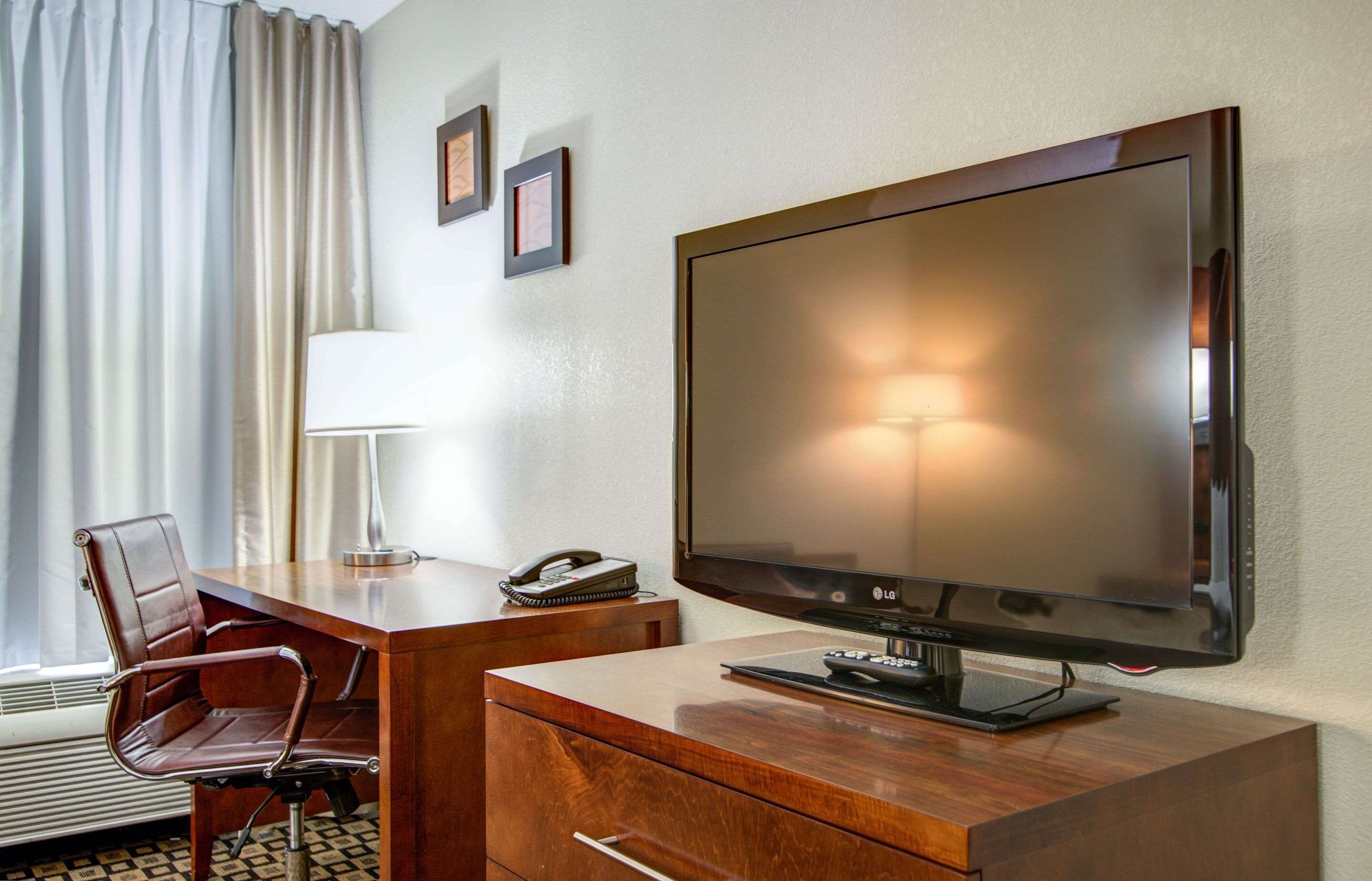 Ein Hotelzimmer mit einem Holztisch, einem Fernseher, einer Lampe und einem Stuhl.