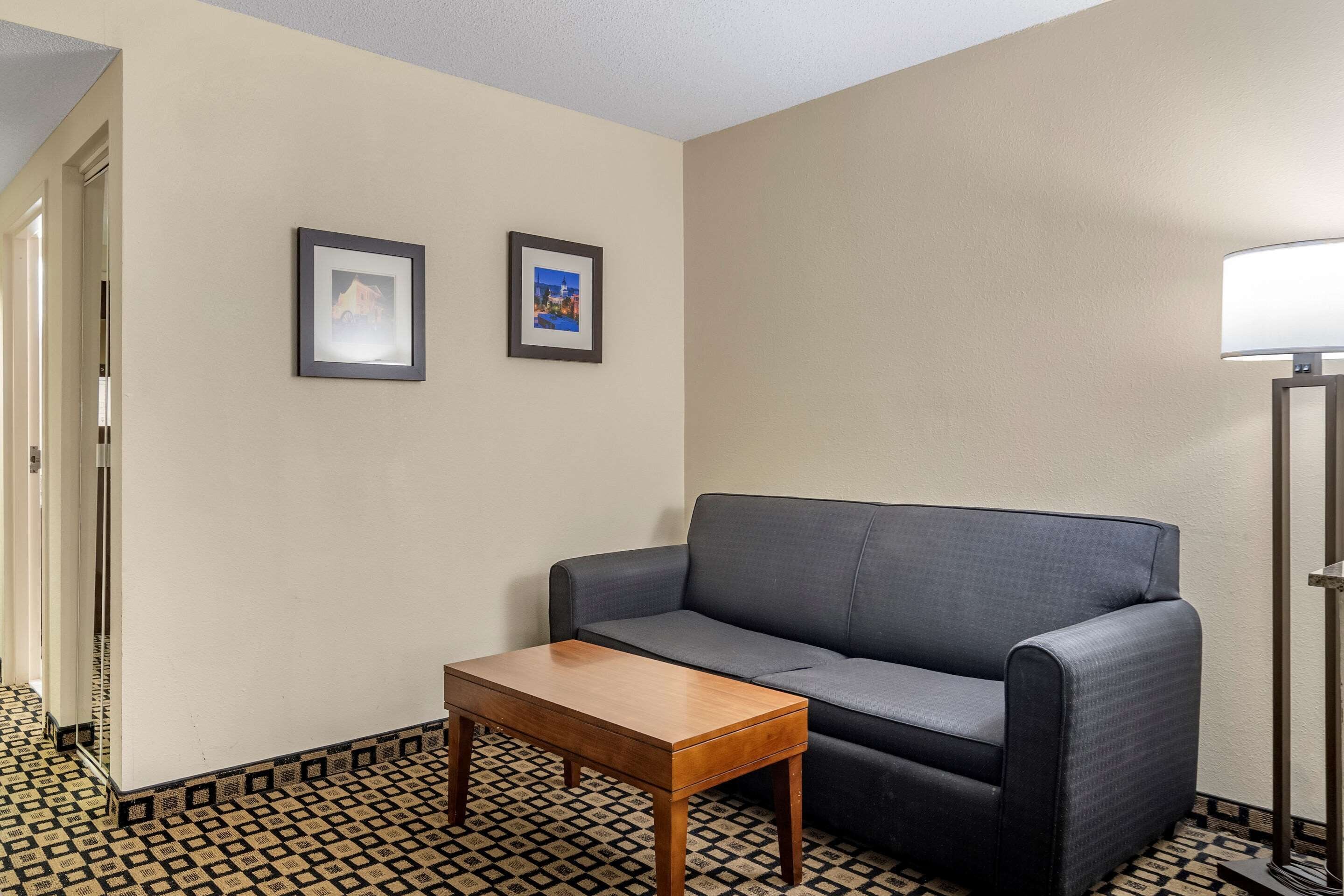 A room with a grey sofa, a wooden side table, and two framed pictures on the wall.