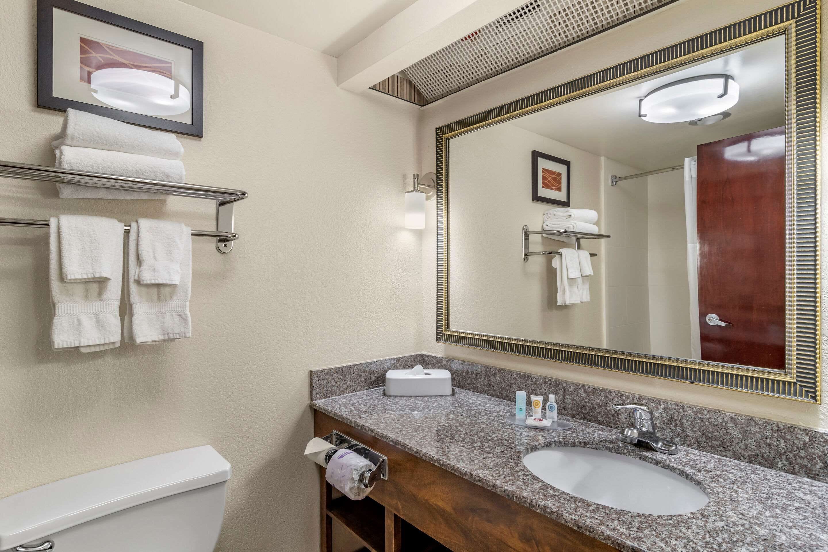 A bathroom with a white sink, a large mirror, and a towel rack with folded towels.