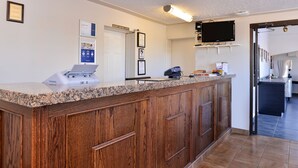 A reception area with a wooden counter, a security desk, a mounted television, and framed certificates on the wall.