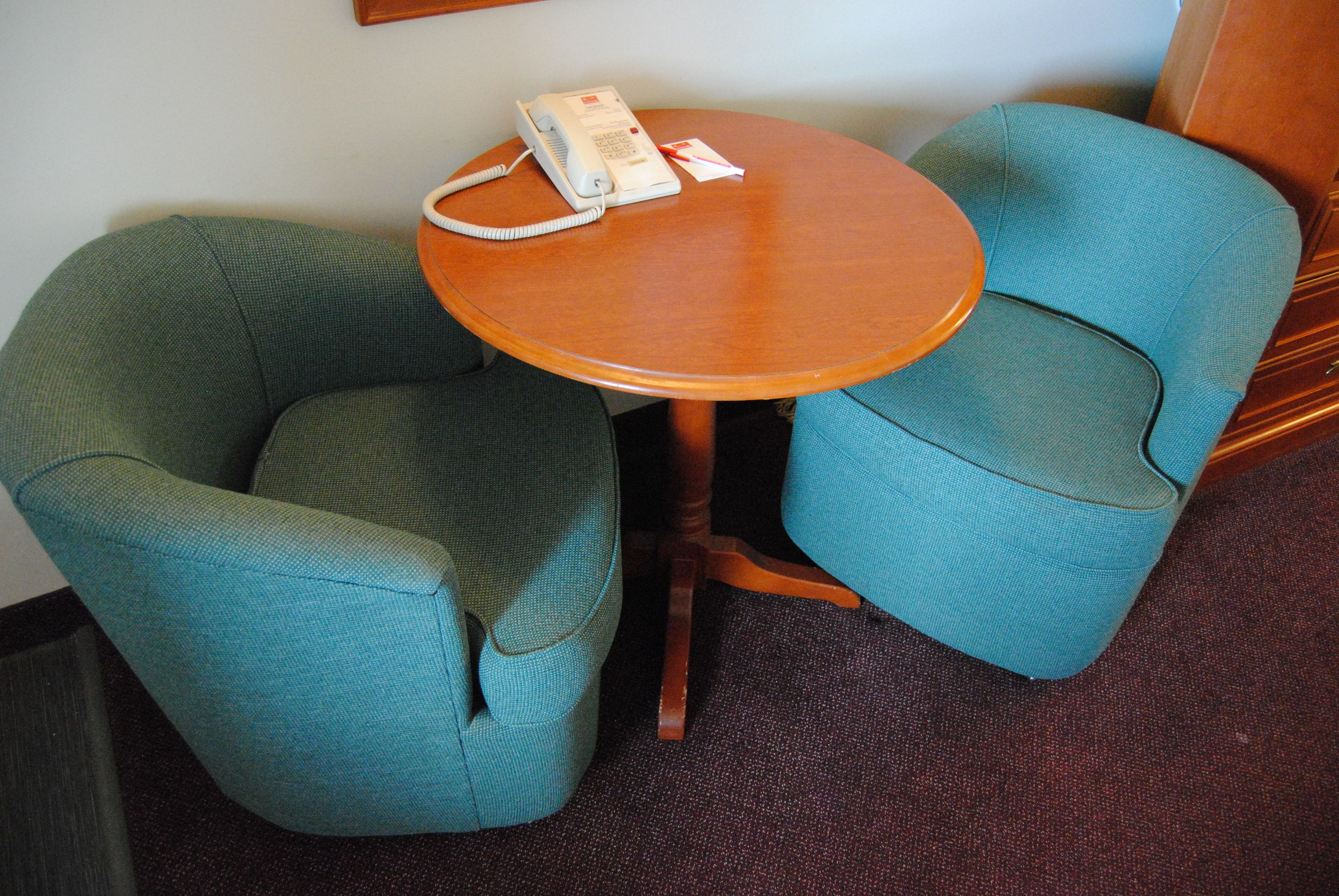 Une pièce avec deux fauteuils turquoise et une petite table en bois.