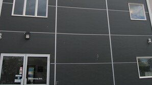 A modern building with a dark facade, large windows, and a flat roof.