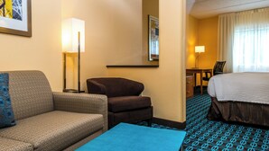 Habitación de hotel con sofá, sillón, escritorio y cama.