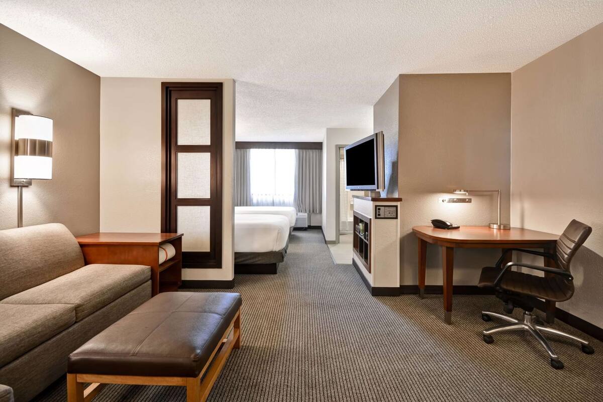 Een hotelkamer met een bank, een bureau met stoel, een televisie en een bed.