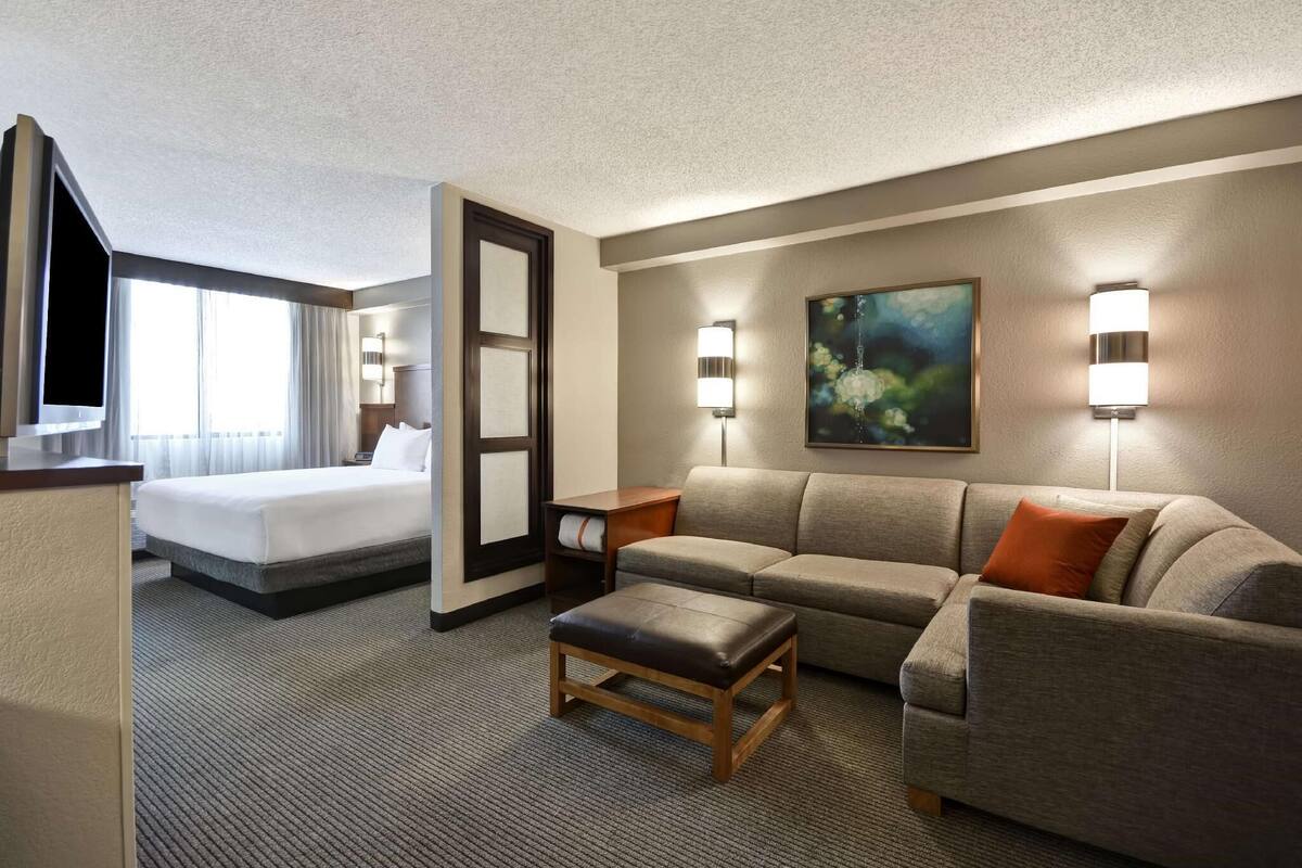 Hotelkamer met een bed, een bank, een salontafel en twee wandlampen.