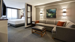 Habitación de hotel con cama, sofá, mesita de café y dos lámparas fijadas a la pared.