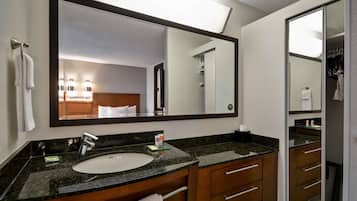 Casa de banho de hotel com um espelho grande, uma pia e uma cómoda com gavetas.