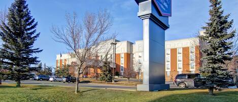 A hotel sign with a modern design, surrounded by a well-maintained lawn and evergreen trees.