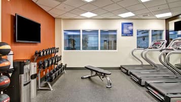 Ett gym med löpband, en bänk och utrustning för styrketräning.