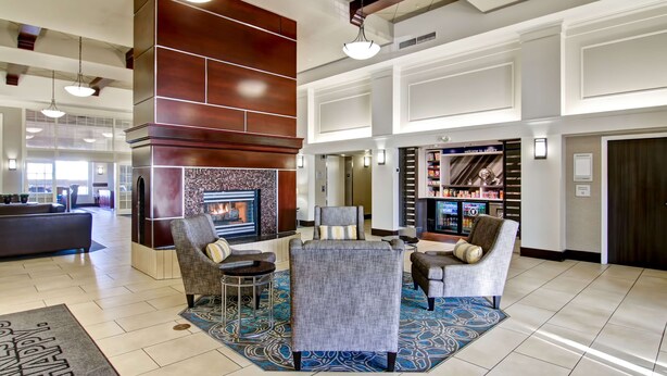 A lobby with a fireplace, seating area, and a reception desk. - Hampton Inn & Suites by Hilton Calgary-Airport (Calgary)
