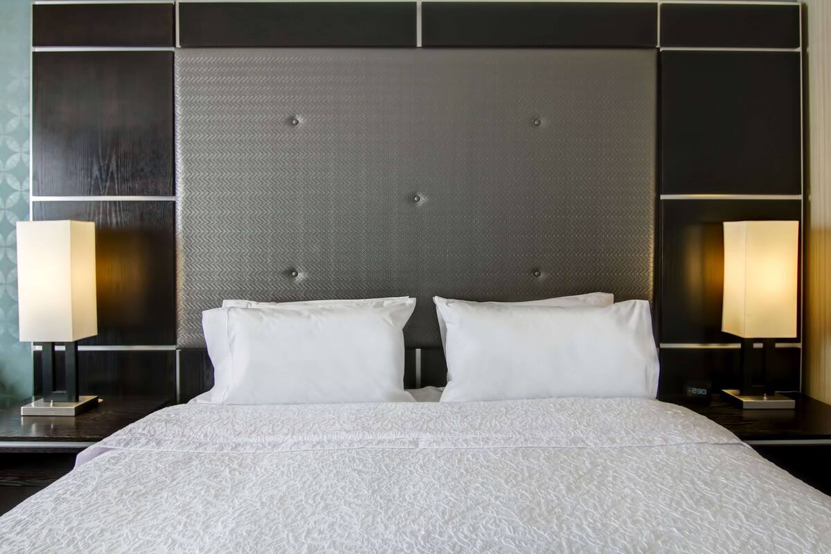A hotel room with a large bed, two bedside lamps, and a modern headboard.