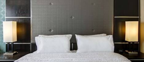 A hotel room with a large bed, two bedside lamps, and a modern headboard.