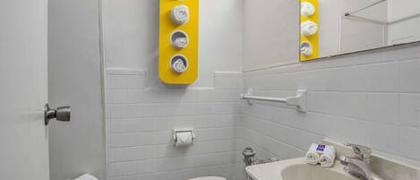 A small, clean bathroom with a toilet, sink, and a yellow towel rack.