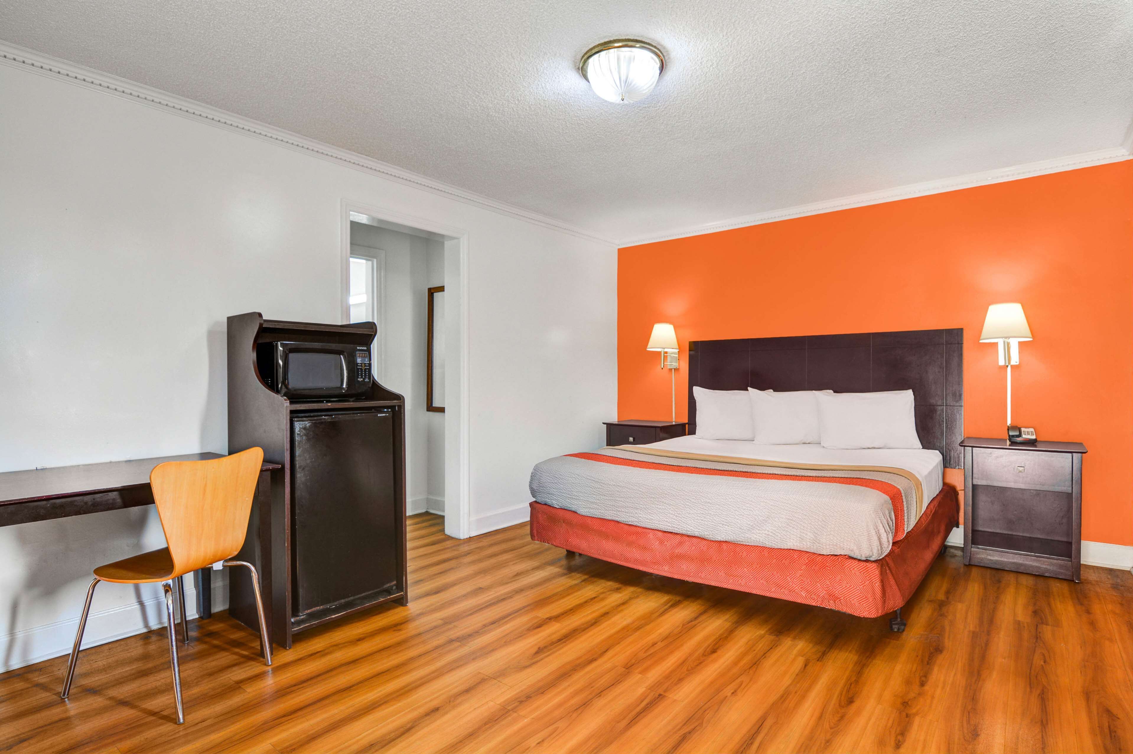 A hotel room with a bed, a desk, a chair, and a television.