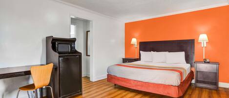 A hotel room with a bed, a desk, a chair, and a television.