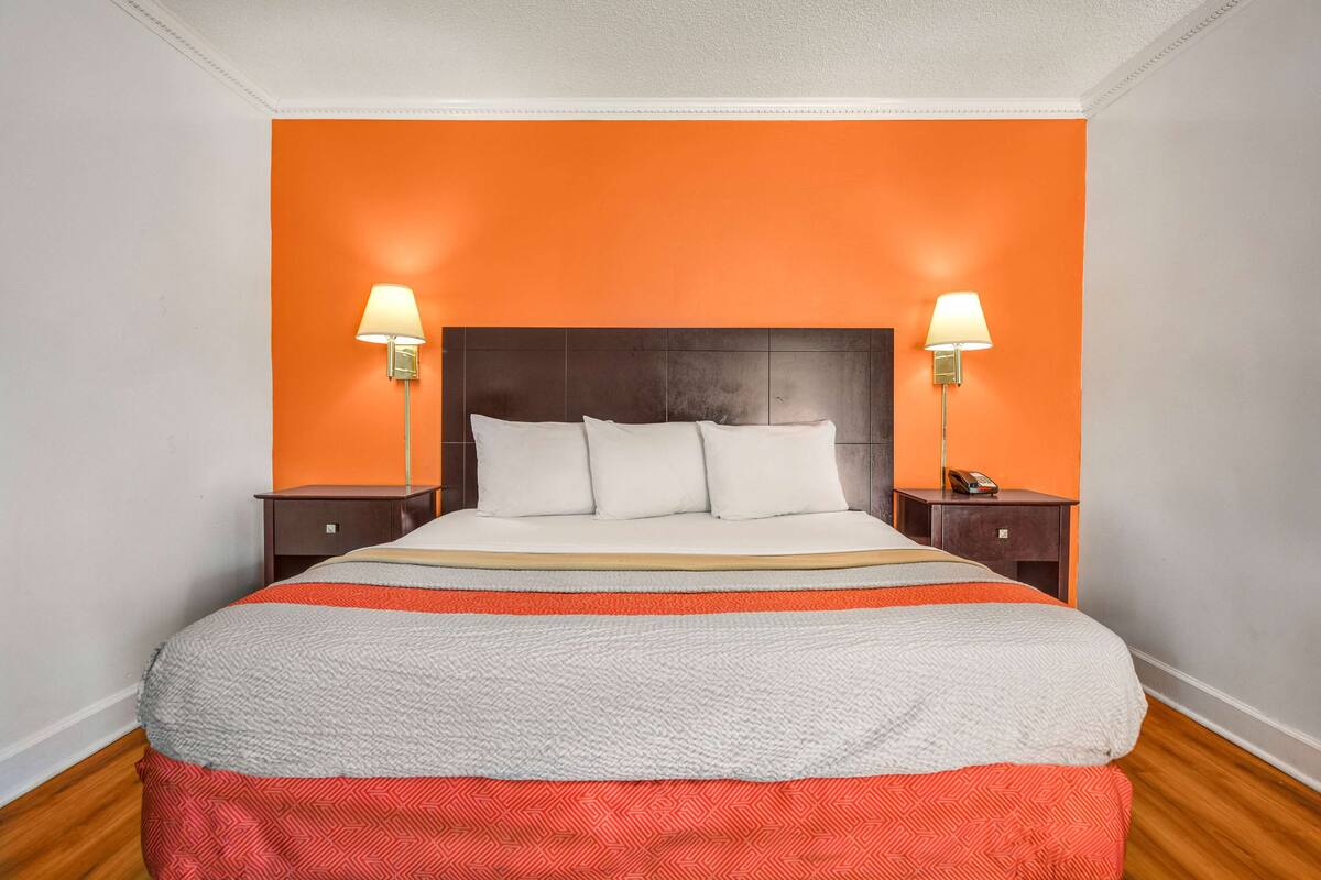 A hotel room with a large bed, two bedside tables, and two wall-mounted lamps.