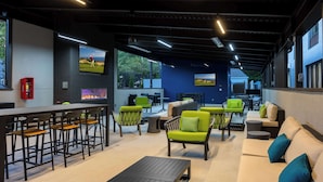 A modern lounge area with bar seating, sofas, and a fireplace. - Hampton Inn & Suites Alpharetta Roswell (Alpharetta)