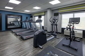 Un gimnasio con cintas de correr, elípticas y una bicicleta estática.